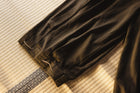 Brown pants with drawstring on a textured beige surface