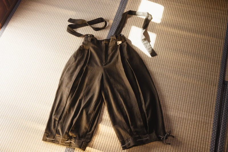 Pair of black pants with suspenders on a textured surface
