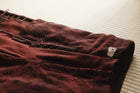 Brown pants with a tag on a light-colored surface