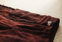 Brown pants with a tag on a light-colored surface